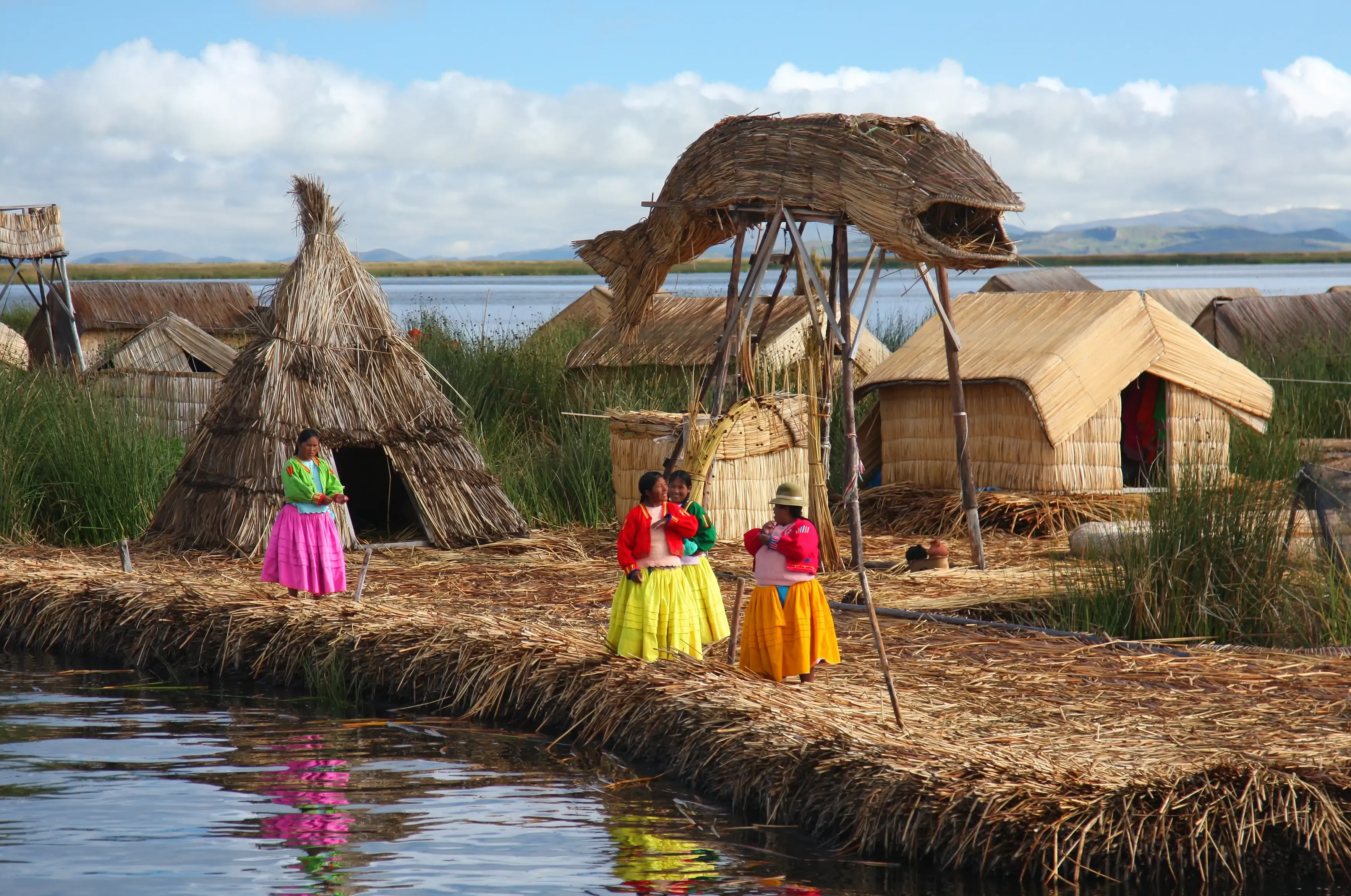 Mulheres em frente a casas e ocas na beira do Lago Titicaca